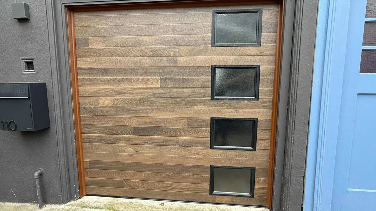 White garage door beside a dark grey wall with a mailbox