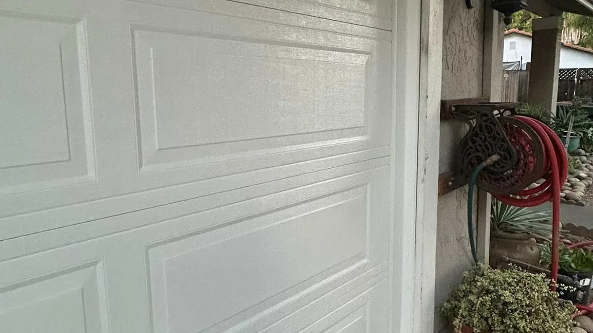 White panel garage door beside a garden side entry