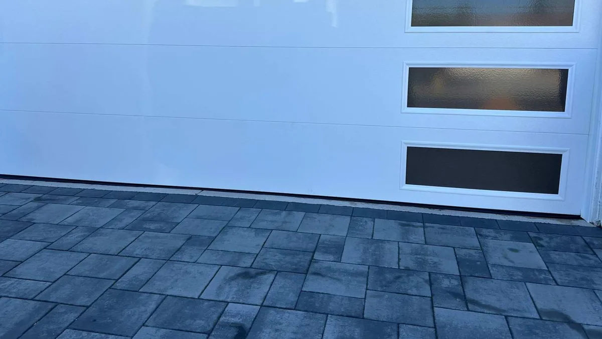 Close view of a wood-grain garage door panel with a single narrow window